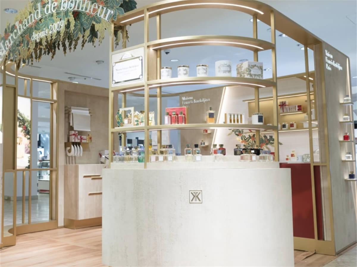 Core counter of perfume kiosk with curved display table, champagne gold multi-tier shelves, and holiday gift sets